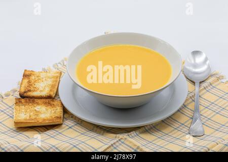 Tradizionale zuppa di panna a base di zucca e carote con pane tostato in un recipiente di ceramica Foto Stock