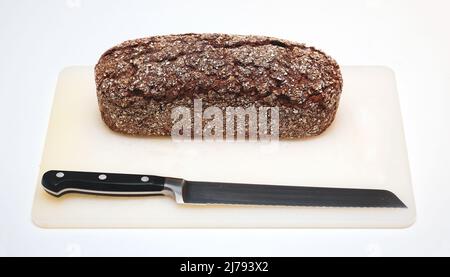 Pane di segale integrale fresco sul tagliere con coltello isolato su sfondo bianco Foto Stock