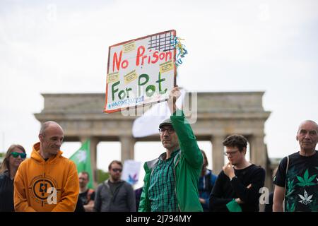 07 maggio 2022, Berlino: Un uomo ha un cartello alla porta di Brandeburgo durante il rally di apertura di una manifestazione per la rapida legalizzazione della cannabis, la "Global Marijuana March 2022". Si legge "No Prison for Pot". Foto: Christoph Soeder/dpa Foto Stock