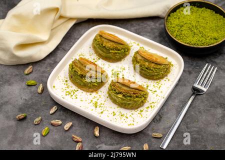 Pistacchio baklava. Baklava con pistacchio su sfondo scuro. Prelibatezze della cucina mediterranea. Primo piano. Nome locale dilber dudagi baklava Foto Stock