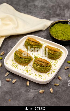 Pistacchio baklava. Baklava con pistacchio su sfondo scuro. Prelibatezze della cucina mediterranea. Primo piano. Nome locale dilber dudagi baklava Foto Stock