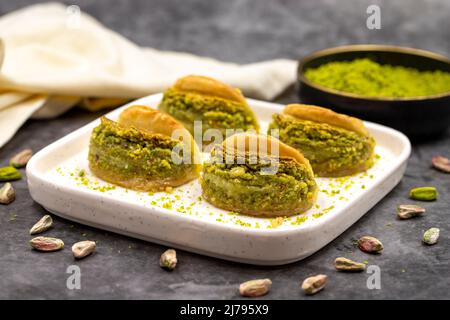 Pistacchio baklava. Baklava con pistacchio su sfondo scuro. Prelibatezze della cucina mediterranea. Primo piano. Nome locale dilber dudagi baklava Foto Stock