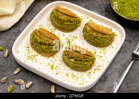 Pistacchio baklava. Baklava con pistacchio su sfondo scuro. Prelibatezze della cucina mediterranea. Primo piano. Nome locale dilber dudagi baklava Foto Stock