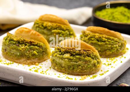 Pistacchio baklava. Baklava con pistacchio su sfondo scuro. Prelibatezze della cucina mediterranea. Primo piano. Nome locale dilber dudagi baklava Foto Stock