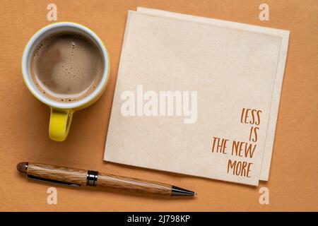 meno è il nuovo più - minimalismo concetto, scrittura a mano su un tovagliolo con una tazza di caffè Foto Stock