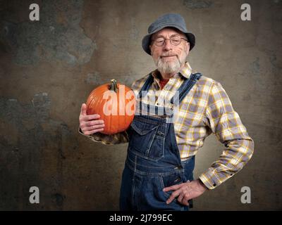 ritratto di un uomo anziano felice e sorridente, barbuto con una zucca dal suo giardino, concetto di giardinaggio Foto Stock