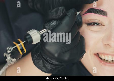 Il maestro di permanente make up esegue sopracciglia microblading in salone di bellezza Foto Stock