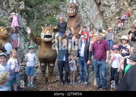 07 maggio 2022, Baden-Wuerttemberg, Weinheim: Grüffelo, il mostro conosciuto da vari libri per bambini, celebra l'apertura del primo sentiero Grüffelo nella Germania meridionale di Weinheim. A destra del Wonding Grüffelo, Marianne Rübelmann, amministratore delegato della Beltz Verlag, con sede a Weinheim, che pubblica i libri Grüffelo, il sindaco di Weinheim Manuel Just, illustratore Grüffelo Axel Scheffler, E dietro di loro a sinistra del Grüffelo di legno, Gert Hildebrandt, artista di motosega che ha creato le sculture di legno sul sentiero. In occasione dell'apertura del sentiero, la città organizza anche Foto Stock