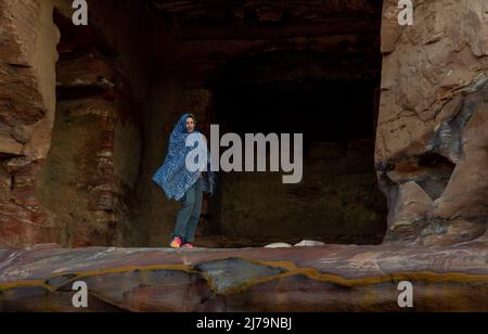 La donna matura si pone a Petra Jordan di fronte al tempio indossando una sciarpa blu e godendo il bellissimo paesaggio scolpito nella roccia a Petra Jord Foto Stock