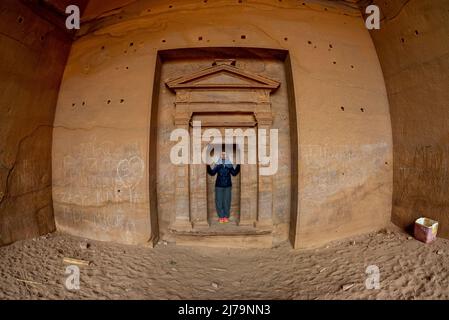 La donna matura si pone a Petra Jordan di fronte al tempio indossando una sciarpa blu e godendo il bellissimo paesaggio scolpito nella roccia a Petra Jord Foto Stock