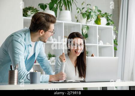 Una donna e un uomo sono felici di un affare di successo in ufficio. Foto Stock