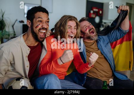 Felici tifosi tedeschi amici che guardano il calcio a casa e festeggiano. Foto Stock