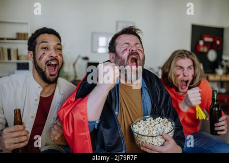 Felici tifosi tedeschi amici che guardano il calcio a casa e festeggiano. Foto Stock