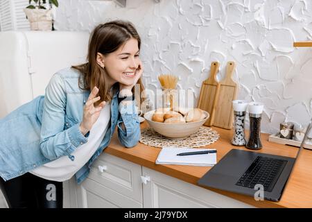 Videochiamata. Lavoro a distanza. La ragazza felice lavora da casa. Comunica tramite videochiamata con i colleghi utilizzando un computer Foto Stock