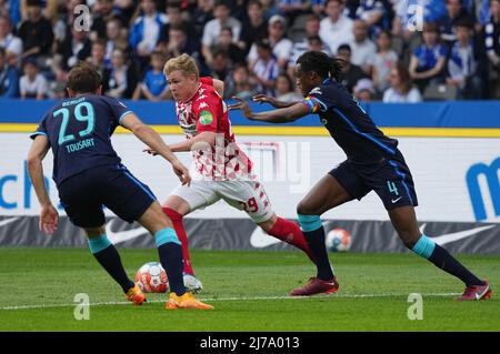 07 maggio 2022, Berlino: Calcio: Bundesliga, Hertha BSC - FSV Mainz 05, Matchday 33, Olympiastadion. Magonza Jonathan Burkardt (M) contro Lucas Tousart di Hertha e Dedryck Boyata di Hertha (r). Foto: Soeren Stache/dpa - NOTA IMPORTANTE: In conformità con i requisiti della DFL Deutsche Fußball Liga e della DFB Deutscher Fußball-Bund, è vietato utilizzare o utilizzare fotografie scattate nello stadio e/o della partita sotto forma di immagini di sequenza e/o serie di foto video-simili. Foto Stock