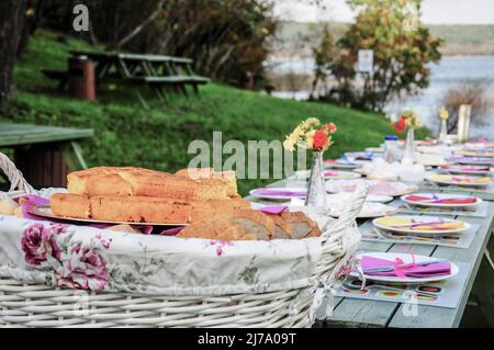 Un tavolo da picnic fantasia pieno di cibo sul lago in estate Foto Stock