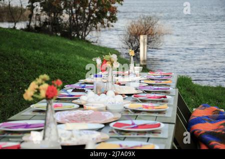 Un tavolo da picnic fantasia pieno di cibo sul lago in estate Foto Stock