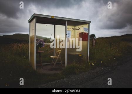 Incredibile luce naturale sulla Scottish Highlands Bus Shelter con sedia e fiori, isola di Skye, Scozia Foto Stock