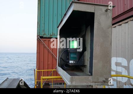 Luci di navigazione verdi a destra della nave container caricata in scatola metallica fissata sulla parte anteriore destra della nave che naviga dal porto Foto Stock