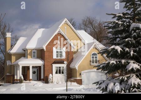 Moderno rosso sfumato mattone e beige legno asse rivestito due piani cottage casa stile paese in inverno. Foto Stock