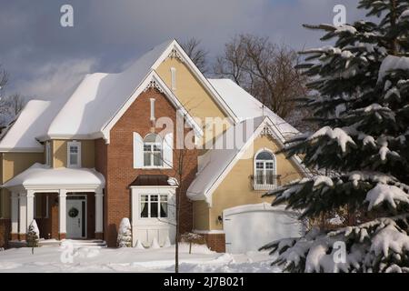 Moderno rosso sfumato mattone e beige legno asse rivestito due piani cottage casa stile paese in inverno. Foto Stock