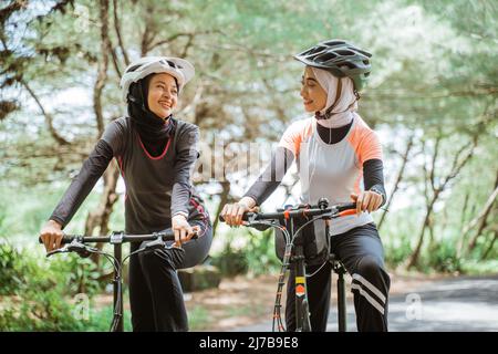 Due donne musulmane in caschi sportivi e ciclistici Foto Stock