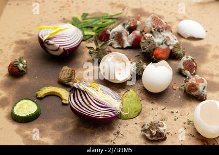 Vista dall'alto di avanzi di cibo marciati su cartone sporco. Frutta marciata, verdure e gusci di uovo gettati per compostaggio. Concetto di rifiuti alimentari residui. Foto Stock