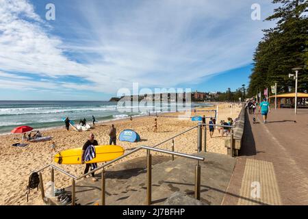 Manly Beach a Sydney, tempo autunnale e surfista lascia la spiaggia accanto a giochi di Beach volley, NSW, Australia Foto Stock