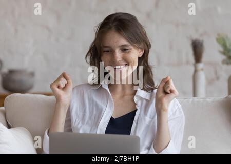 Utente allegro di un notebook che guarda il display, facendo sì che il vincitore si mani Foto Stock