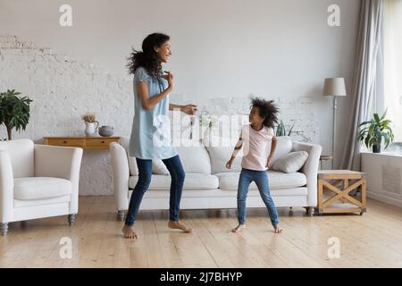 Felice eccitato mamma e figlia attiva che ballano alla musica Foto Stock