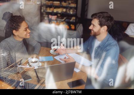 Allegro giovane gare miste startupers brainstorming e collaborare in caffè al laptop. Foto Stock