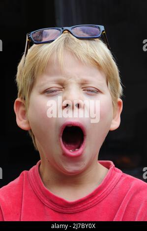 portait di un ragazzino che gela con gli occhiali sulla testa , concetto di bambini stanchi o assonnati . Foto Stock