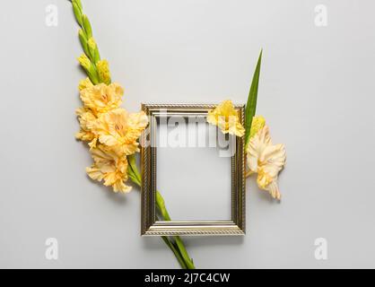 Cornice vuota e fiori di gladiolo su sfondo grigio Foto Stock