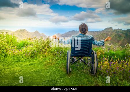 Donna con disabilità in sedia a rotelle sulla collina di montagna che gode di vista Foto Stock