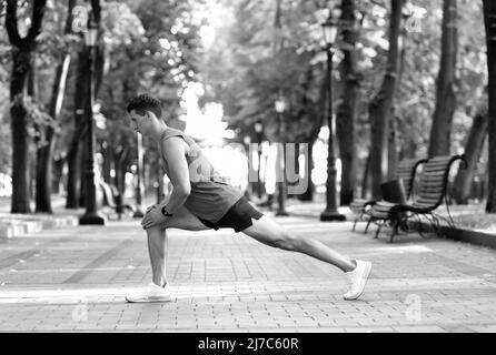 Scaldati prima dell'allenamento. Uomo prendere il riscaldamento. Posizione di affondo di mantenimento sportivo. Esercizi di riscaldamento Foto Stock