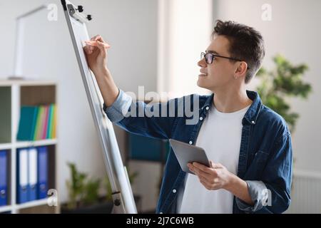 Pianificazione avvio. Giovane imprenditore maschio che tiene il tablet digitale e la scrittura a bordo Foto Stock