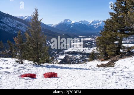 Affacciato sulla città di Banff dalla cima del Tunnel Mountain Trail in inverno. Sedia rossa nella neve. Banff National Park, Canadian Rockies. Foto Stock