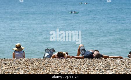 Brighton UK 8th May 2022 - i visitatori godono di una calda giornata di sole sulla spiaggia di Brighton e sul lungomare, come si prevede che le temperature raggiungano oltre 20 gradi in alcune parti del Regno Unito: Credit Simon Dack / Alamy Live News Foto Stock