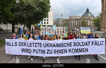 08 maggio 2022, Baviera, Monaco: I partecipanti di un raduno contro la guerra in Ucraina marciano attraverso il centro della città con una bandiera che legge 'se l'ultimo soldato ucraino cade. Putin verrà da voi”. Foto: Karl-Josef Hildenbrand/dpa Foto Stock