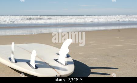 Surfboard per il surf sdraiato sulla spiaggia di sabbia, costa californiana, USA. Onde oceaniche e tavole da surf bianche o paddleboard. Longboard o sup per la ricreazione di sport acquatici con acqua di mare. Cinematografia senza giunture. Foto Stock