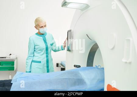 Medico femminile in maschera di assistenza durante MRI per l'uomo Foto Stock