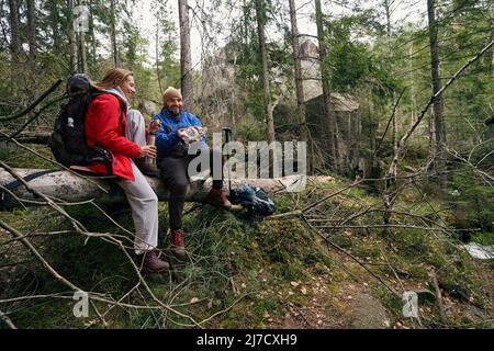 Coppia di escursionisti che prendono un morso su albero caduto Foto Stock