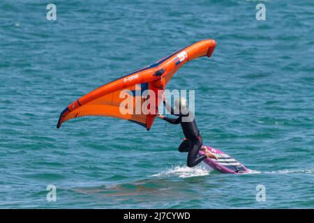 Surf con lamina utilizzando una tavola da surf con aliscafo subacqueo lame che si alzano in superficie quando in movimento, e una vela gonfiabile tenuta a mano Foto Stock