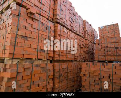 Pallet con mattoni rossi sono immagazzinati in un'area aperta Foto Stock