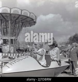 1960s, storica, due giovani ragazze seduti in un giro di divertimento ad un funfair, Inghilterra, Regno Unito. Foto Stock