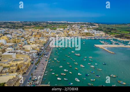 Vista panoramica aerea di Marsaxlokk - piccolo e tradizionale villaggio di pescatori nella regione sudorientale di Malta con molte barche di pescatori colorate Foto Stock
