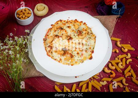 Formaggio di pollo Cashew Nuts pasta in un piatto vista laterale su sfondo di legno Foto Stock