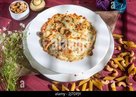 Formaggio di pollo Cashew Nuts pasta in un piatto vista laterale su sfondo di legno Foto Stock