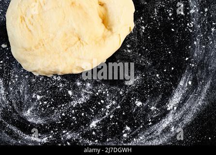 Pasta cruda su superficie nera infarinata, occupazione panettiere Foto Stock