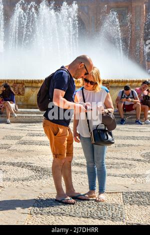 Coppia turistica guardare cellulare in Plaza de Espana a siviglia sevilla Spagna Foto Stock